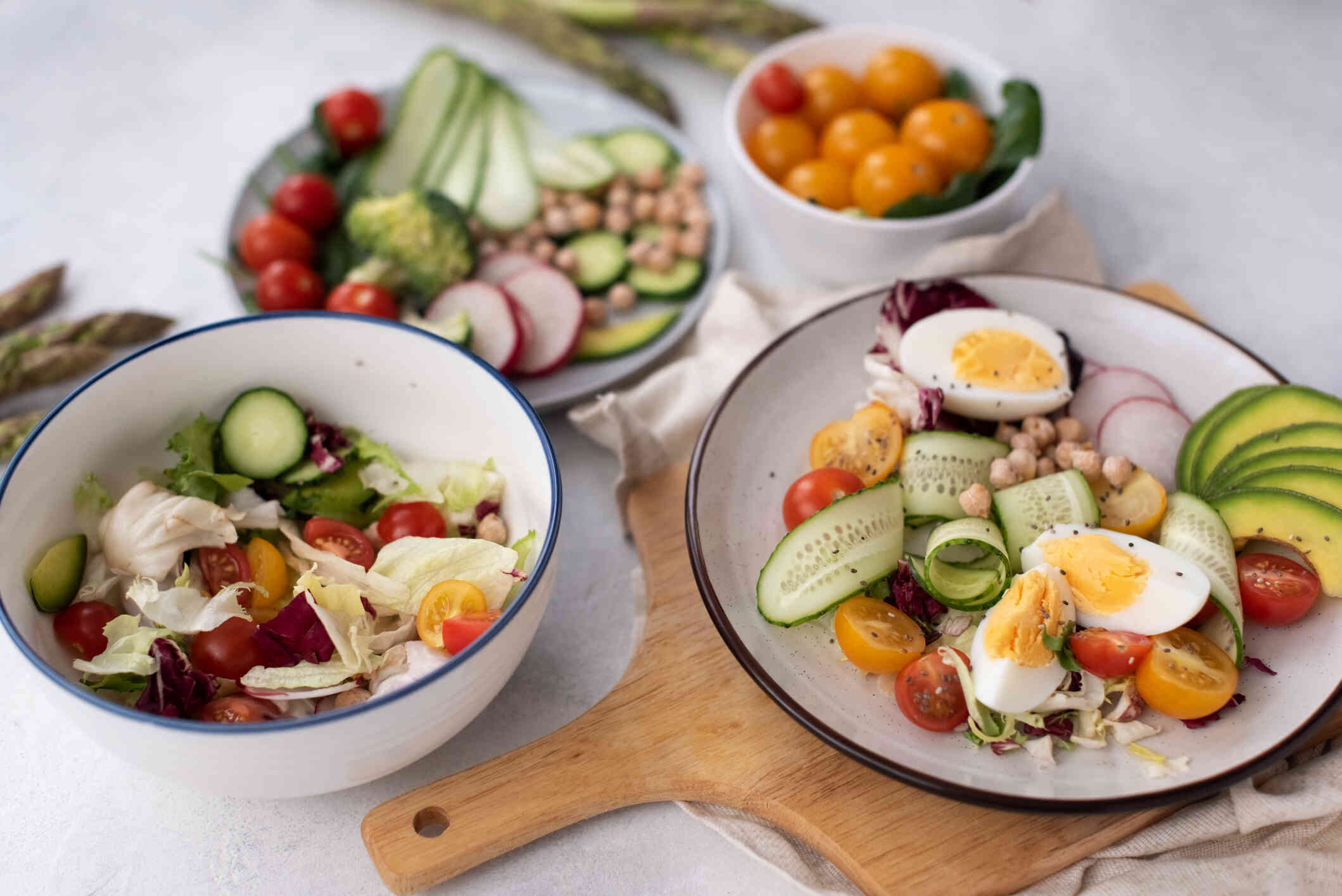 A close up image of four bowls filled with cooked vegetables and cherry tomatoes which are sitting on a table.