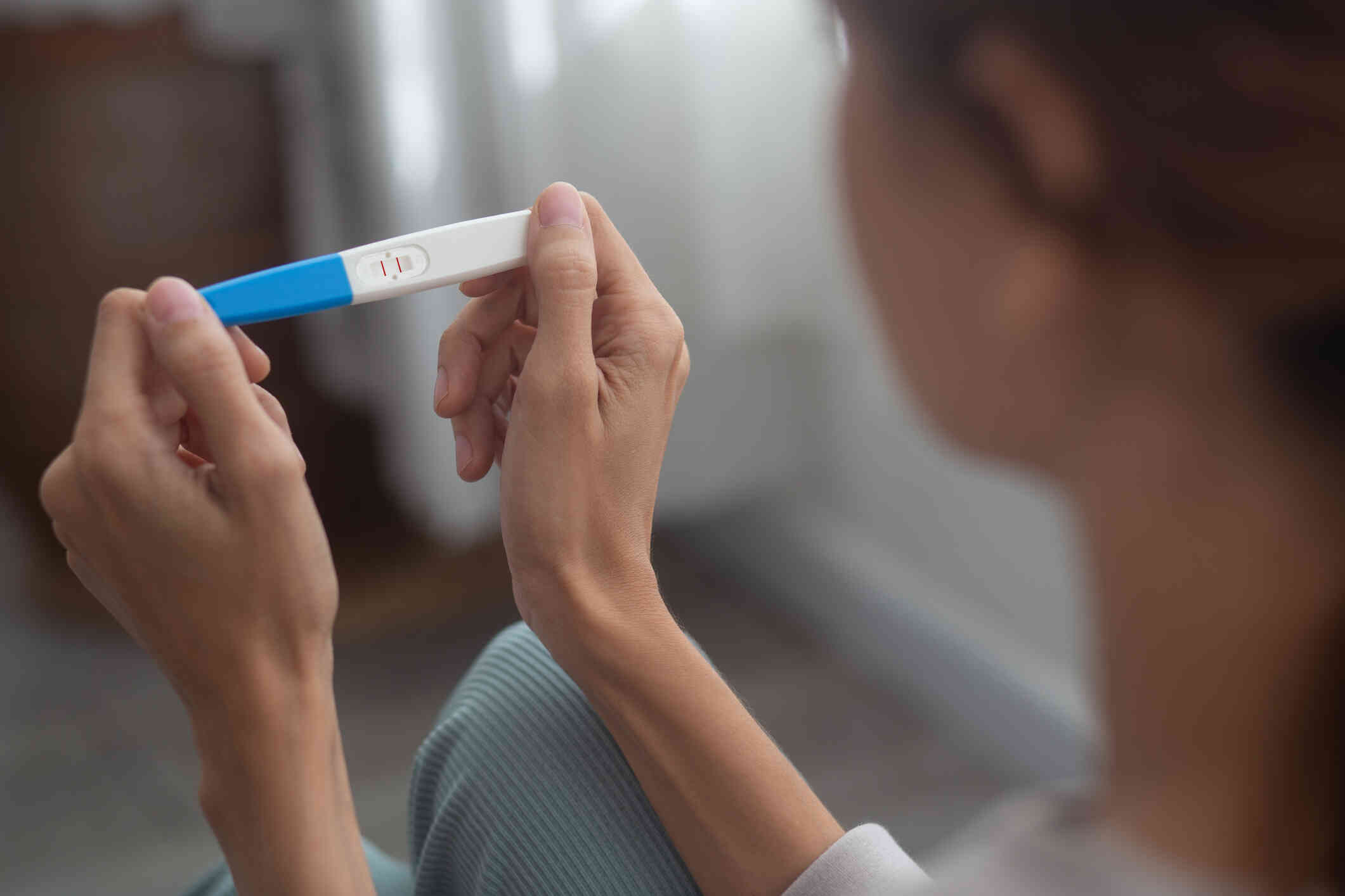 A close up of a woman looking at a pregnancy test in her hands.