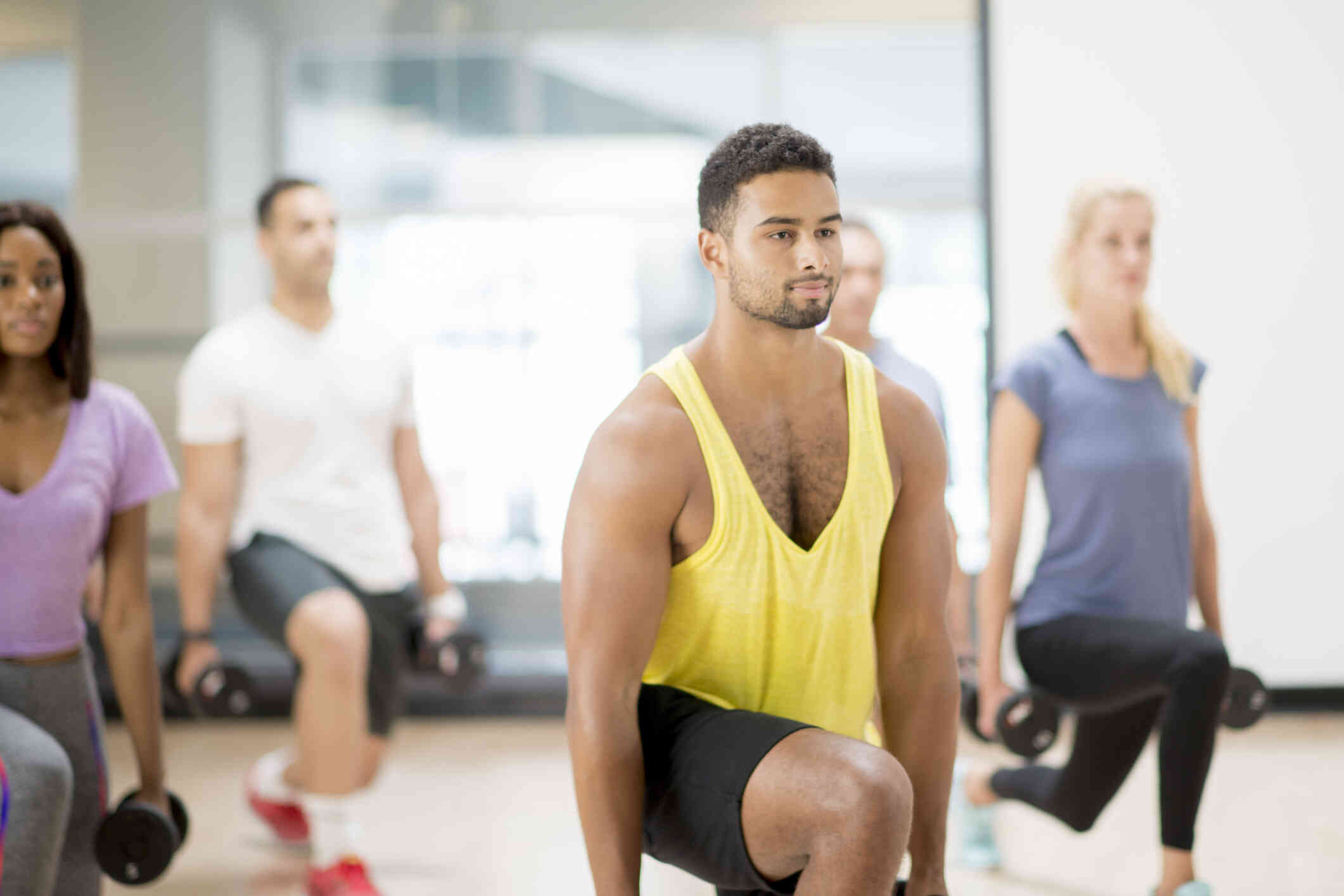 A group of adults in workout clothes lift weights during a workout class.