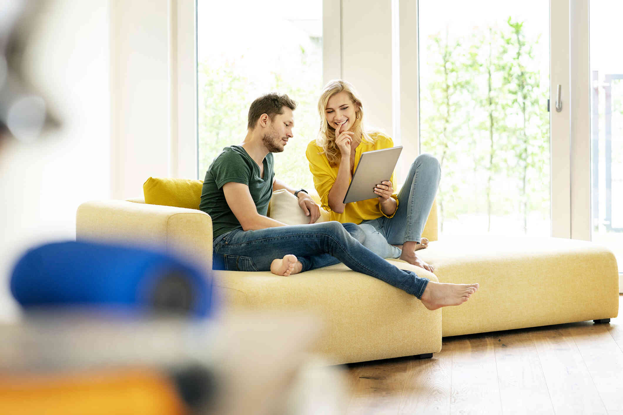 A couple sits comfortably in a couch while looking at the iPad.