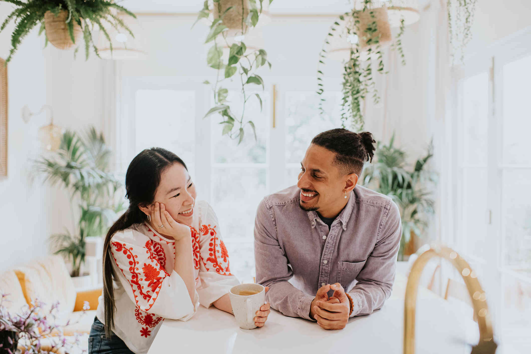 A male and female couple smile what sitting at a table in a room full of house plants.
