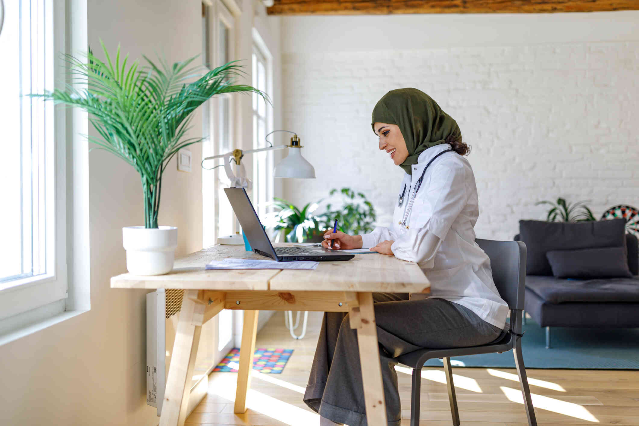 A woman sits at a table and leans into the laptop infront of her while reading about the code of ethics on the screen.