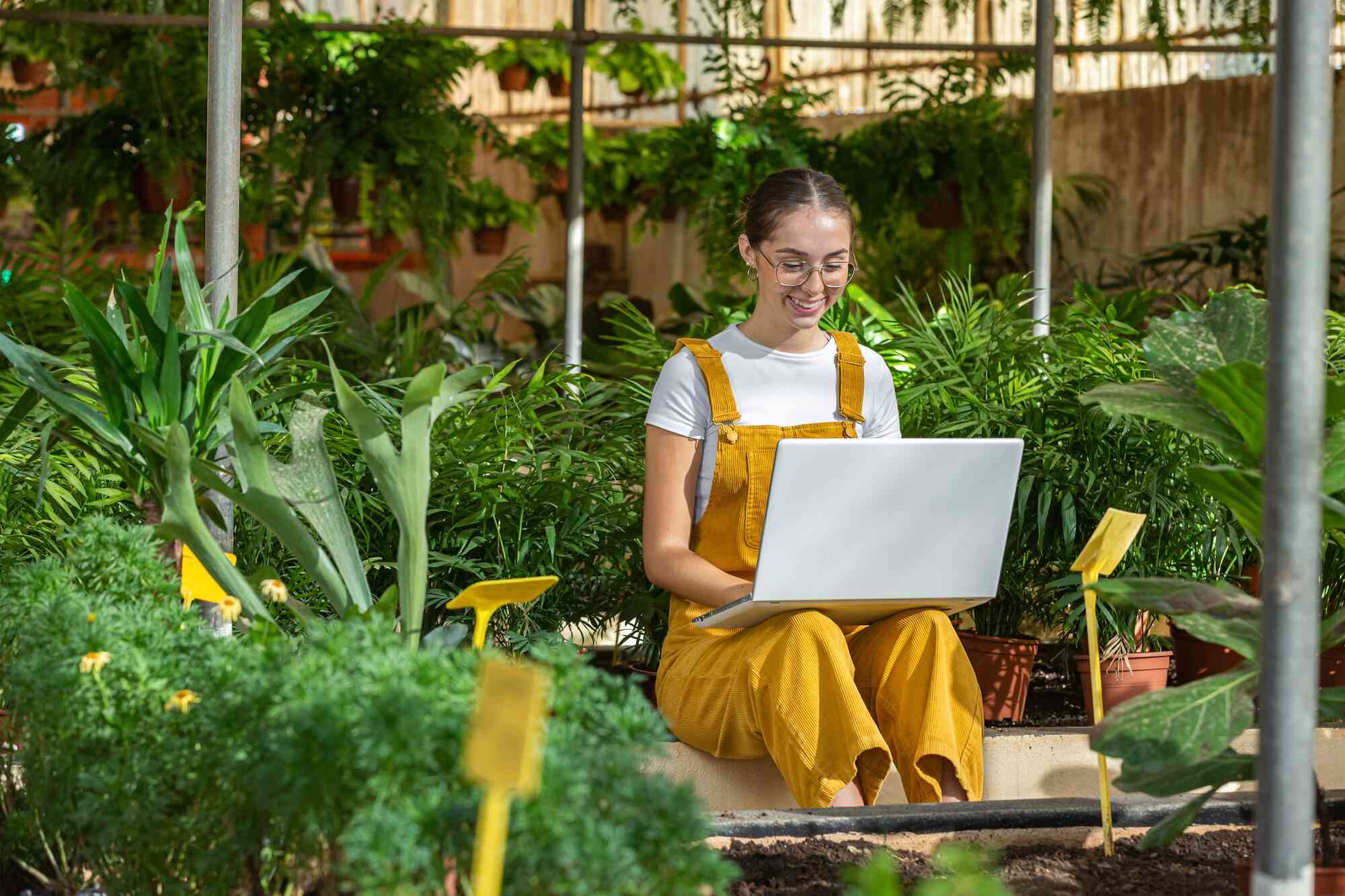 A woman sits outside on the step while looking at her laptop.