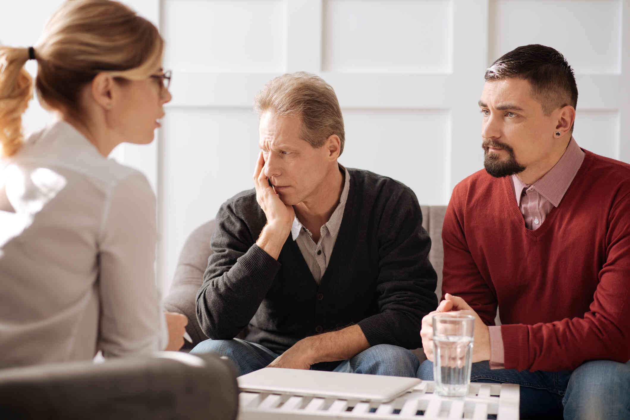 A couple discussing a serious matter to a therapist seated in front of them.