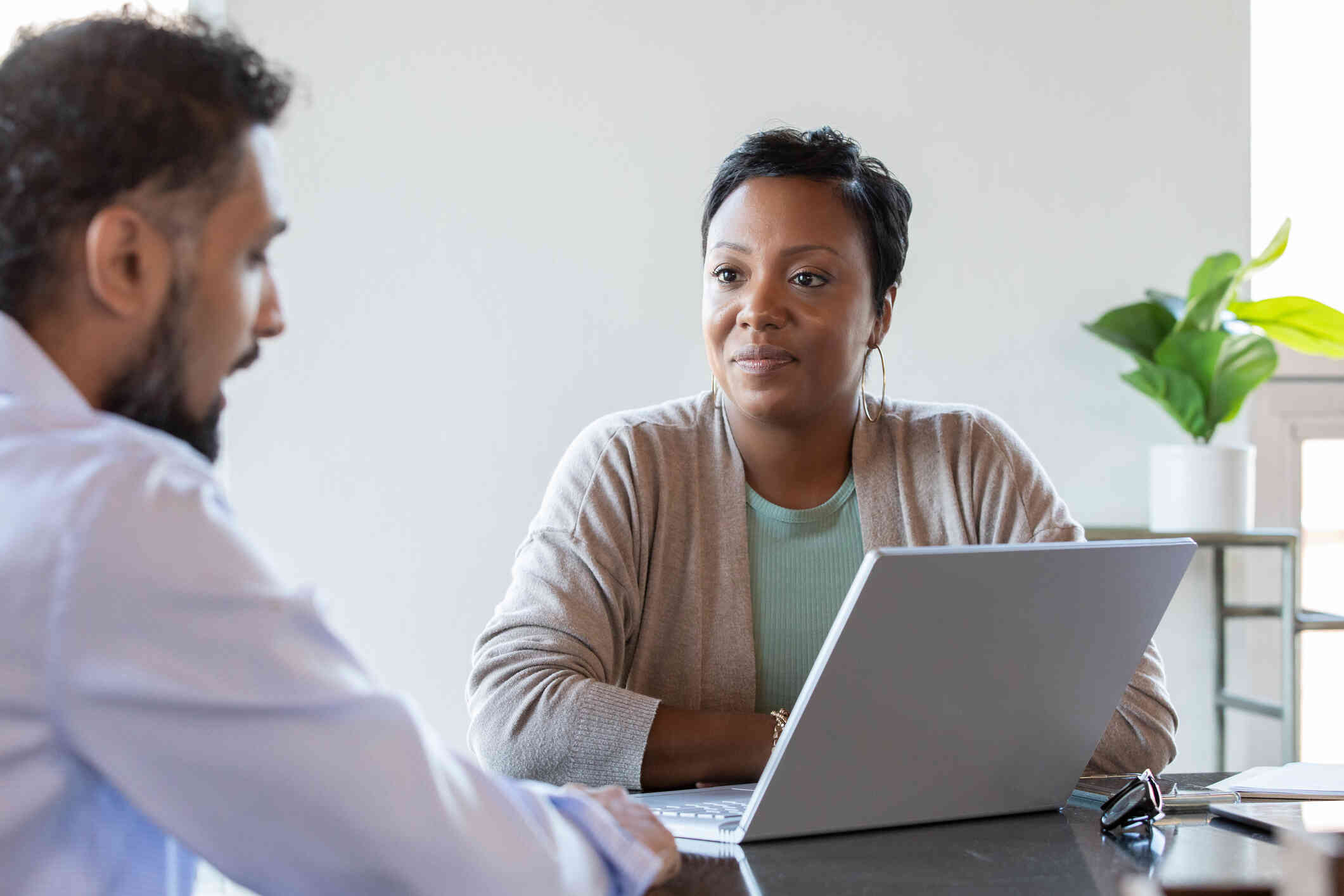 A close up of a female therapist as she sits across from her male patient and listens to him talk.