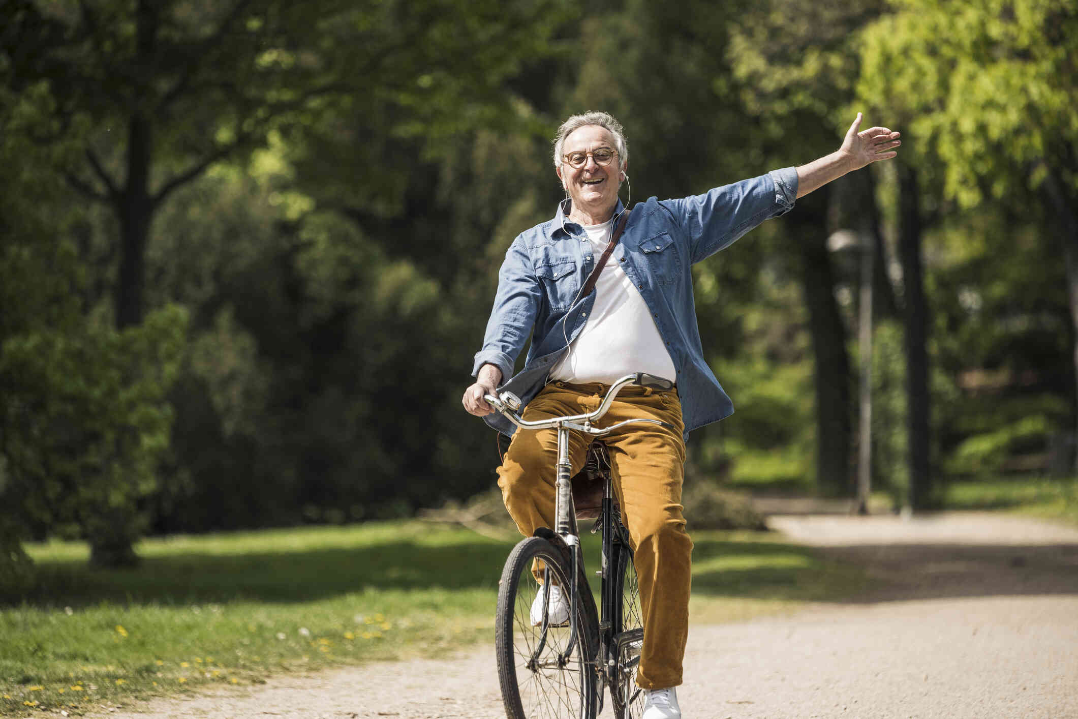 A middle aged man rides his bicycle with excitement while outside on a sunny day.