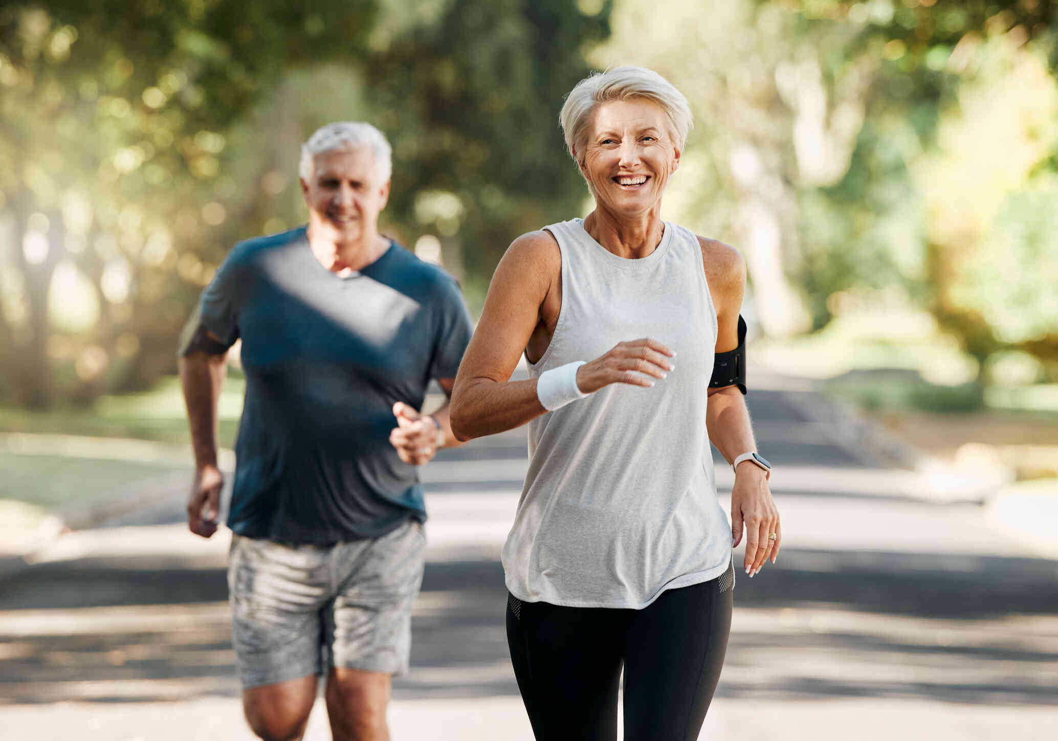 A mature male and female couple go for a jog  together on a sunny day.