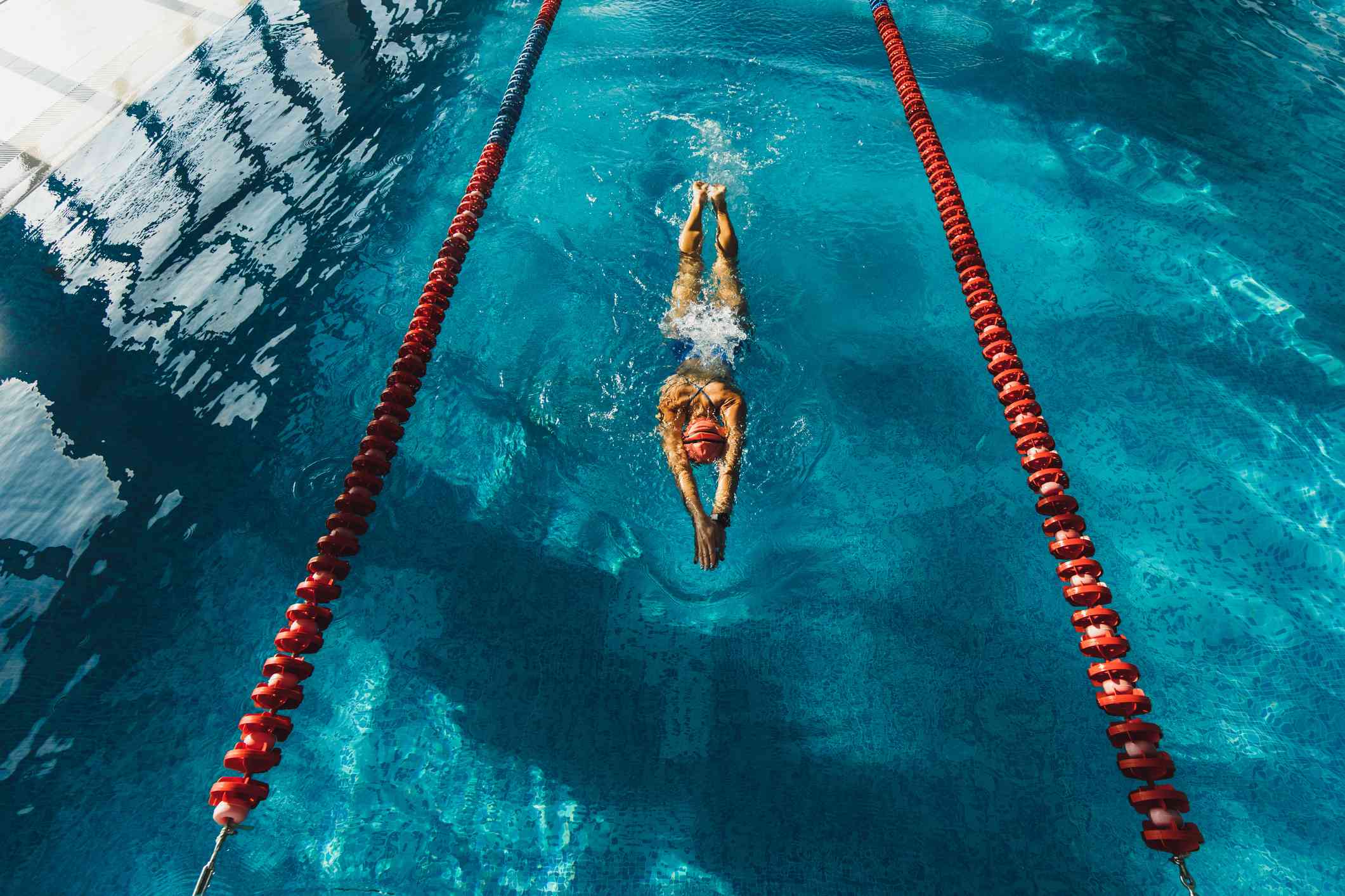 A woman in a swim cap swims laps in a pool.