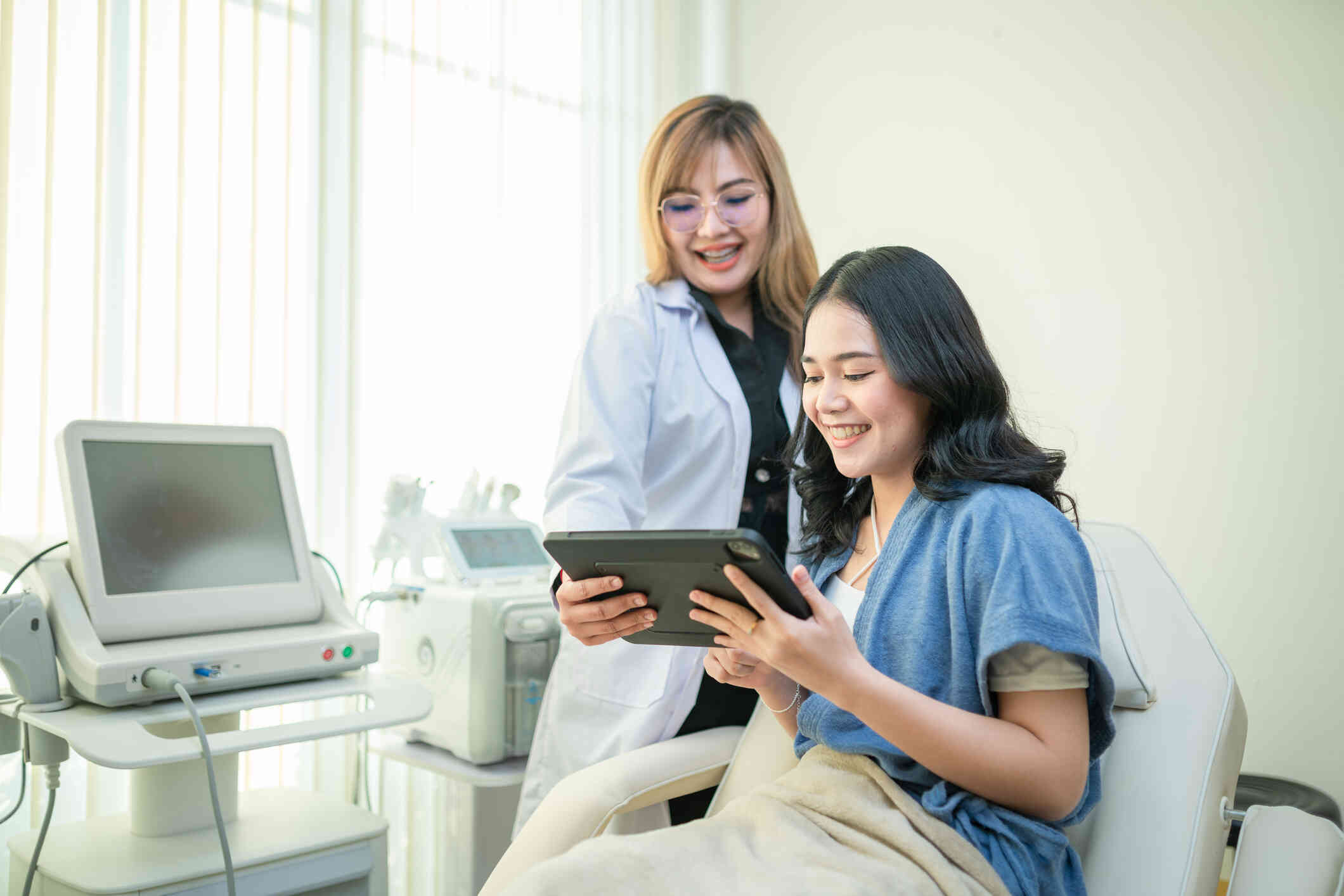 A woman smiling at a tablet that a doctor is showing her.