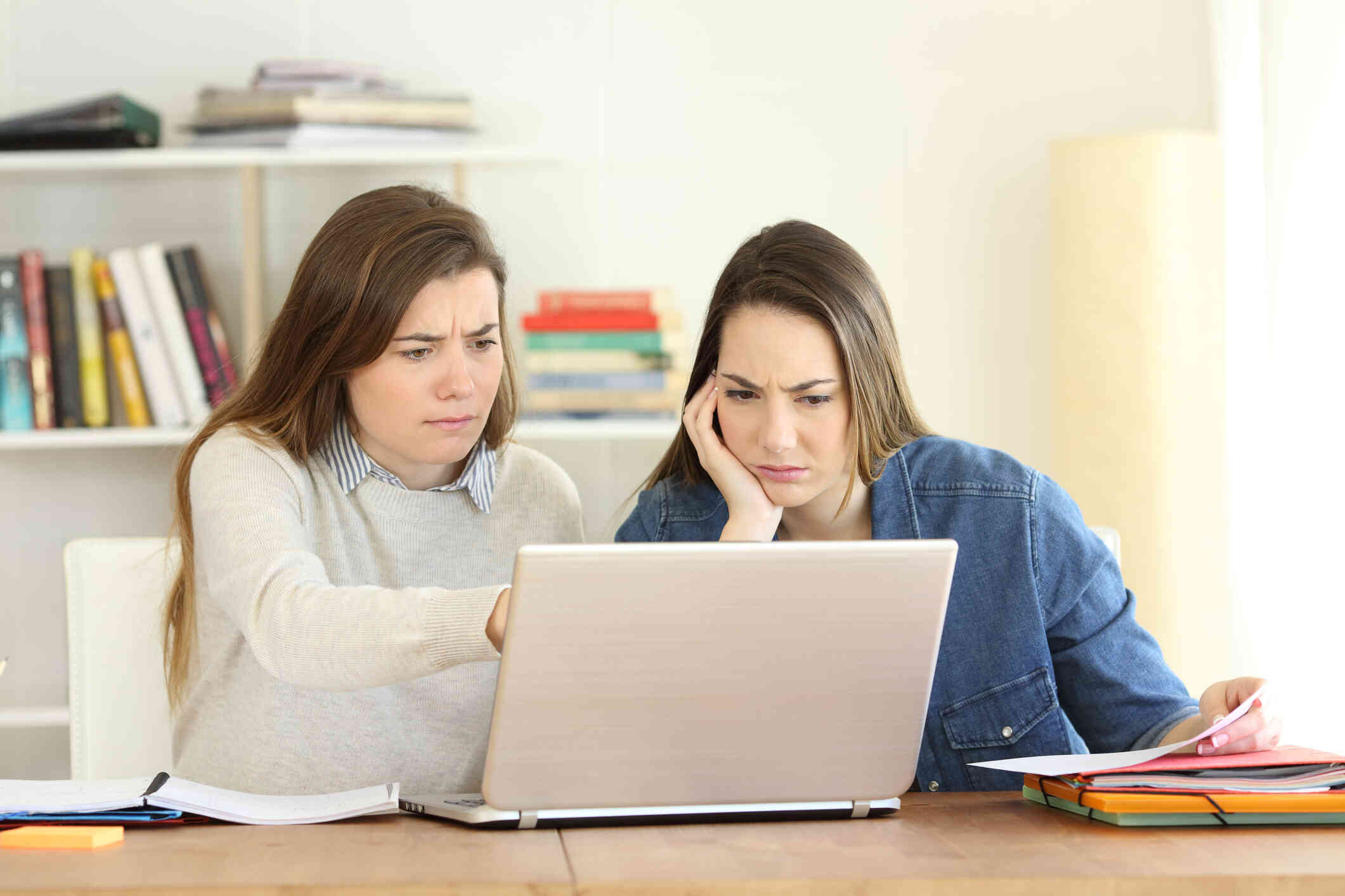 Two women appear distressed while checking something on the laptop.