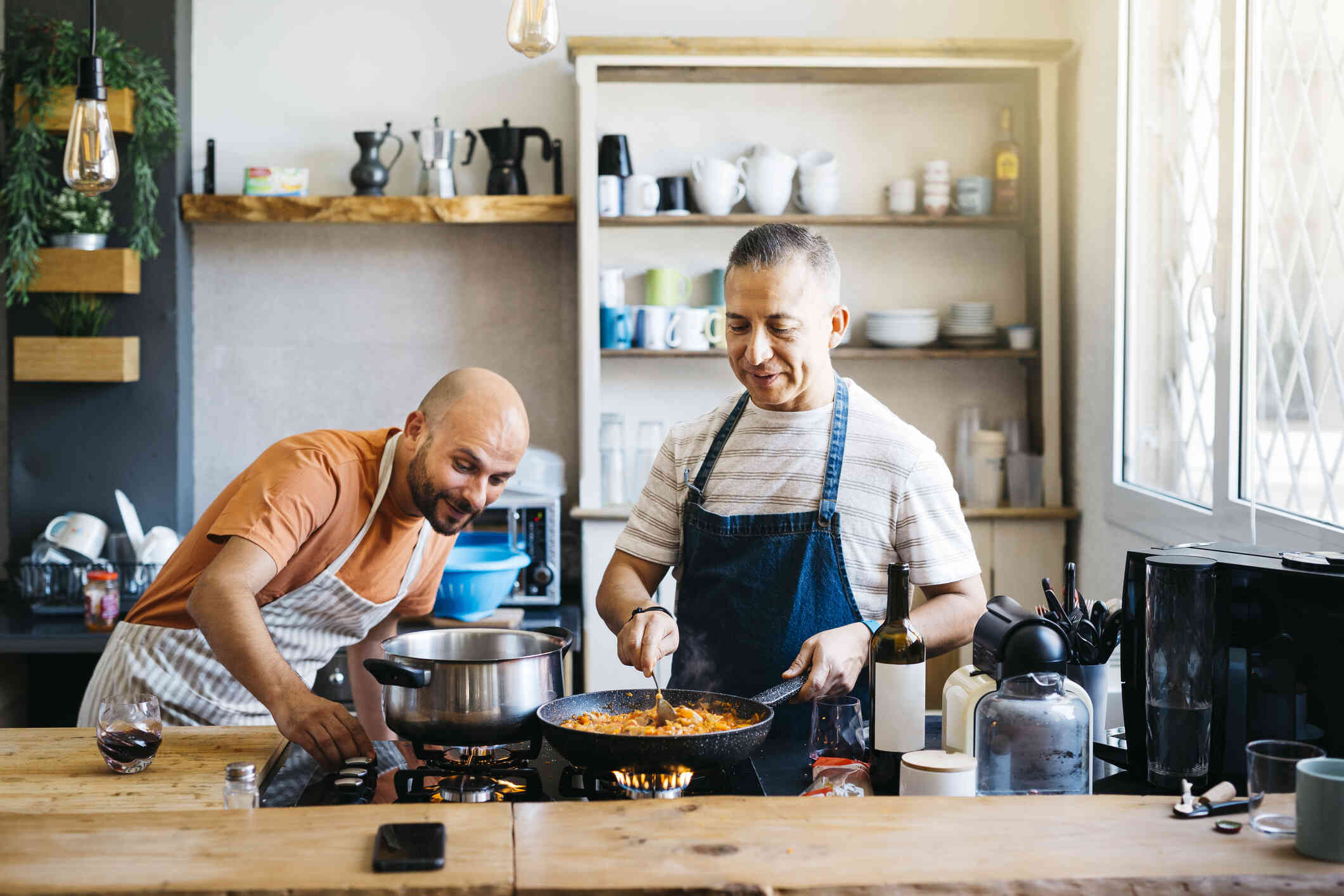 Two middle aged men cook in the kitchen together.