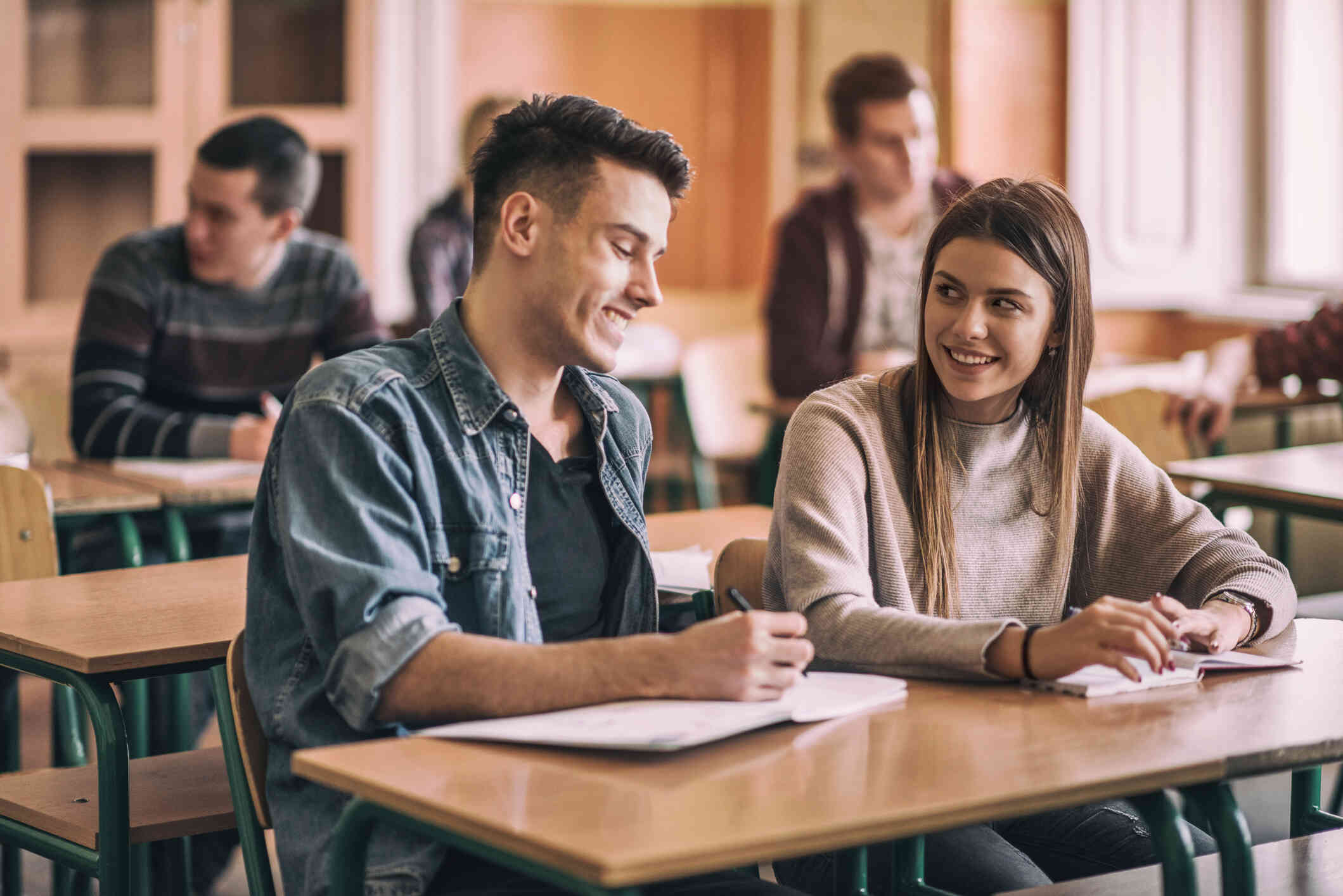 A group of college students sit at their desk in a classroom.