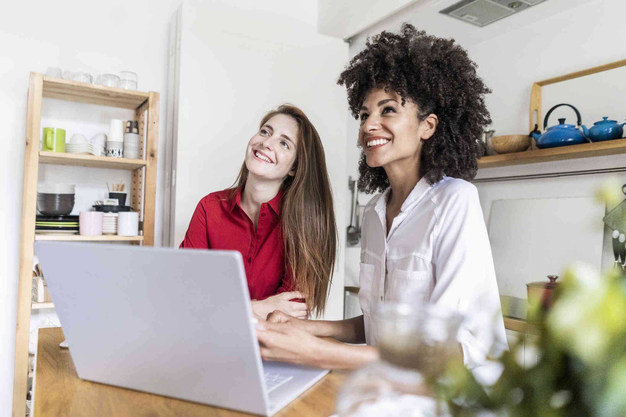 Two women smile as they look something in front of them.