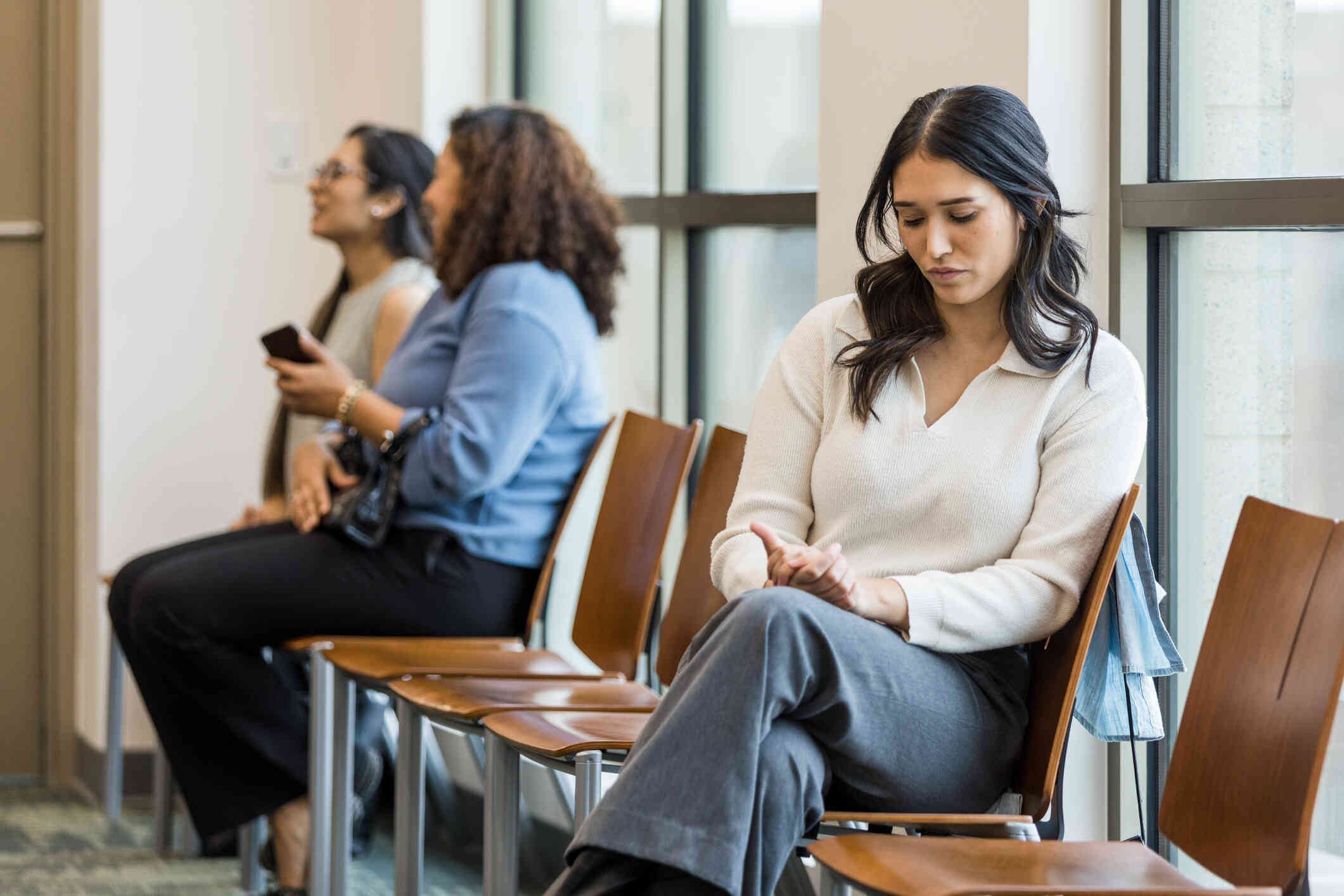 A woman looks upset while sitting by herself in a crowded room.