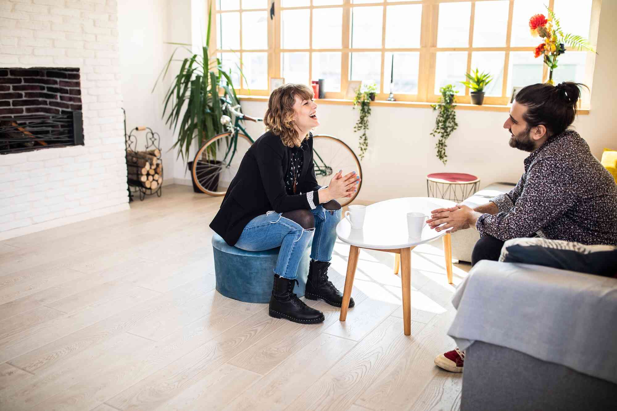 A woman sits in a chair smiling while talking to a man across from her who is also smiling