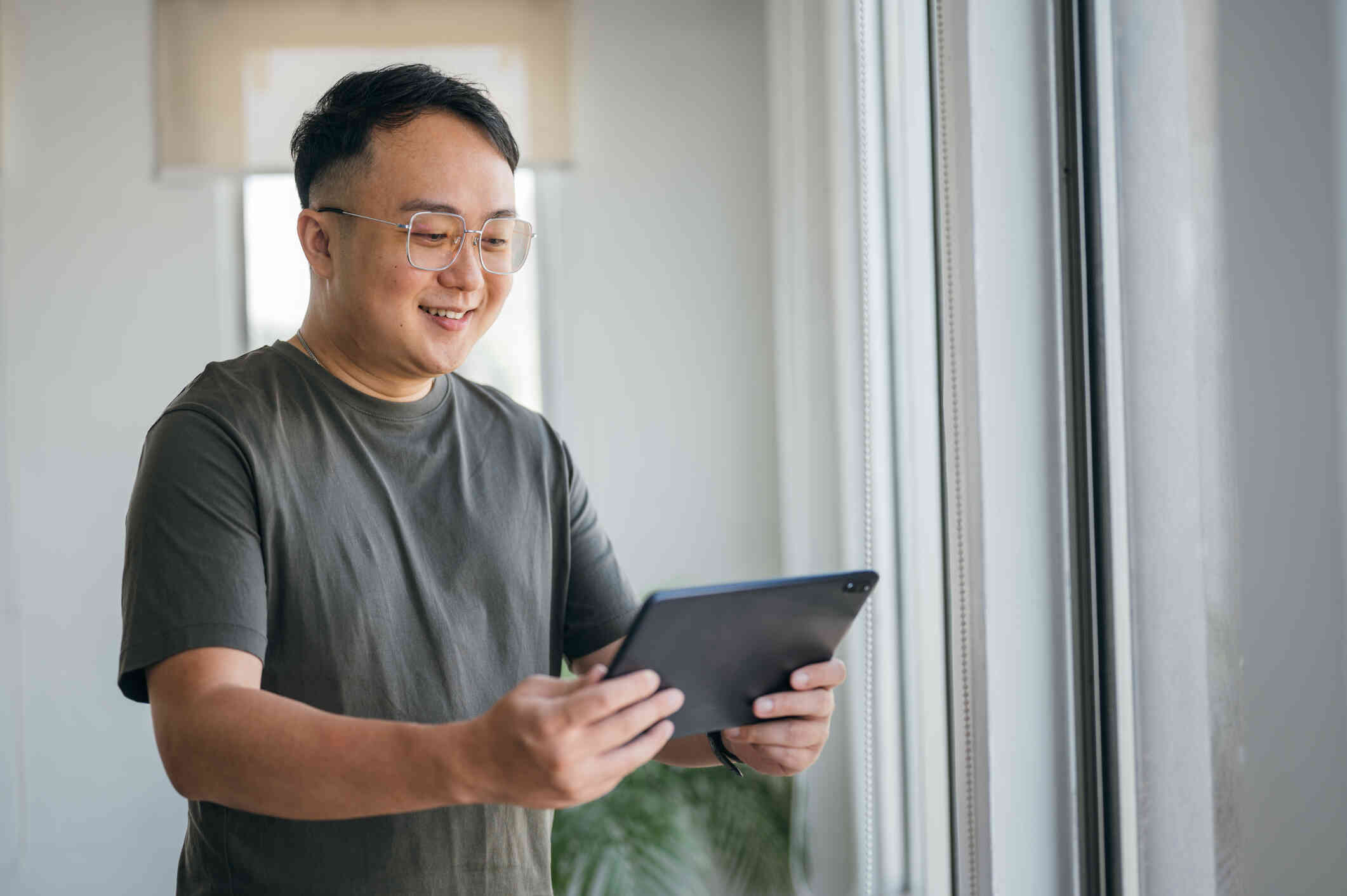 A man holds a tablet while smiling at the camera